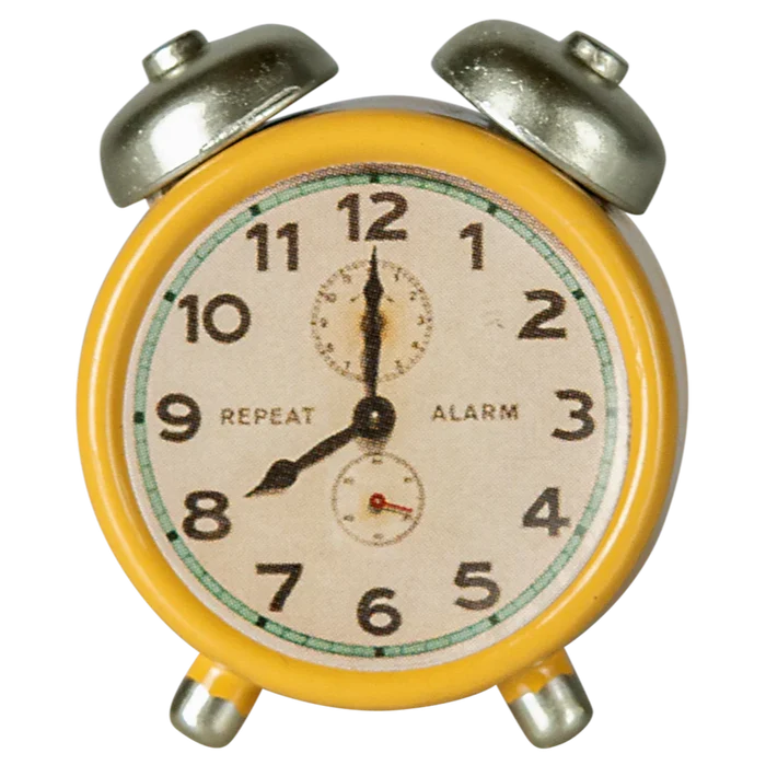 A small yellow and silver metal alarm clock with a white clock face and black numerals.