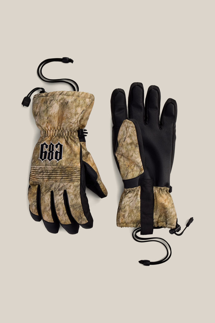A pair of 686 Men’s Lander™ Gloves featuring a camouflage design, black palms, and adjustable wrist cords; one glove is adorned with the 686 logo in black and white on the back.