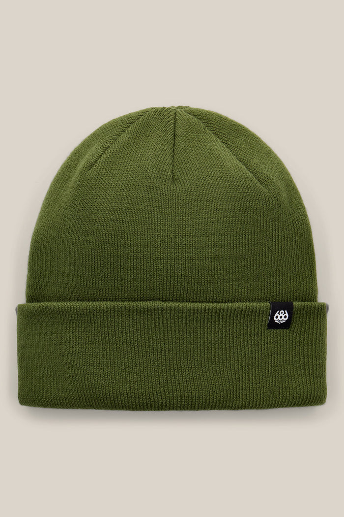 The 686 Standard Roll Up Beanie by 686 is a plain olive-green knit beanie with a folded brim, featuring a small black tag with a white logo on the side, displayed against a neutral beige background.