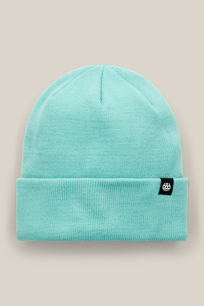 The 686 Standard Roll Up Beanie by 686 is a light turquoise knit hat featuring a folded brim and a small black rectangular tag with a white logo, shown against a neutral beige background.