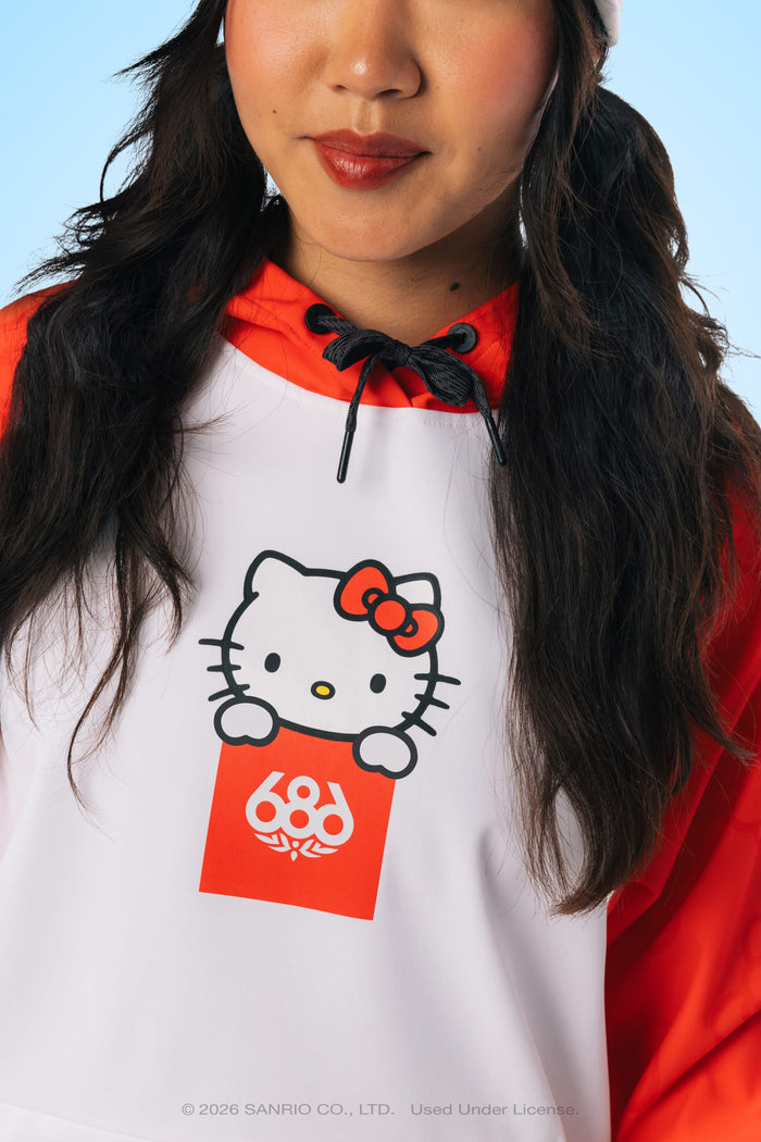 A woman wearing the 686 Women’s Hello Kitty® Waterproof Hoody from 686, featuring a white and orange design with Hello Kitty holding a red sign on the front. Only her lower face and upper torso are visible, highlighting the stylish woven hoody.