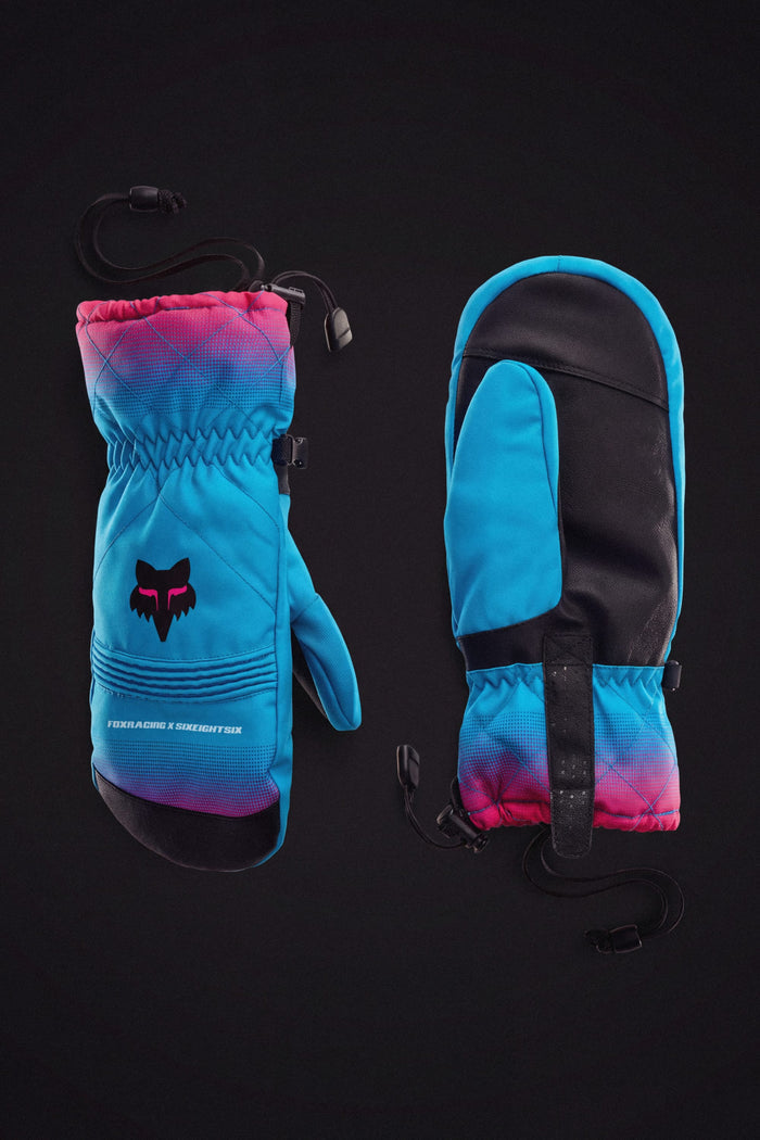 Two blue and pink 686 Women’s Jubilee™ Mitts with black palms—one displays the fox logo, the other shows the palm, both featuring adjustable wrist straps and waterproof insulation on a black background.