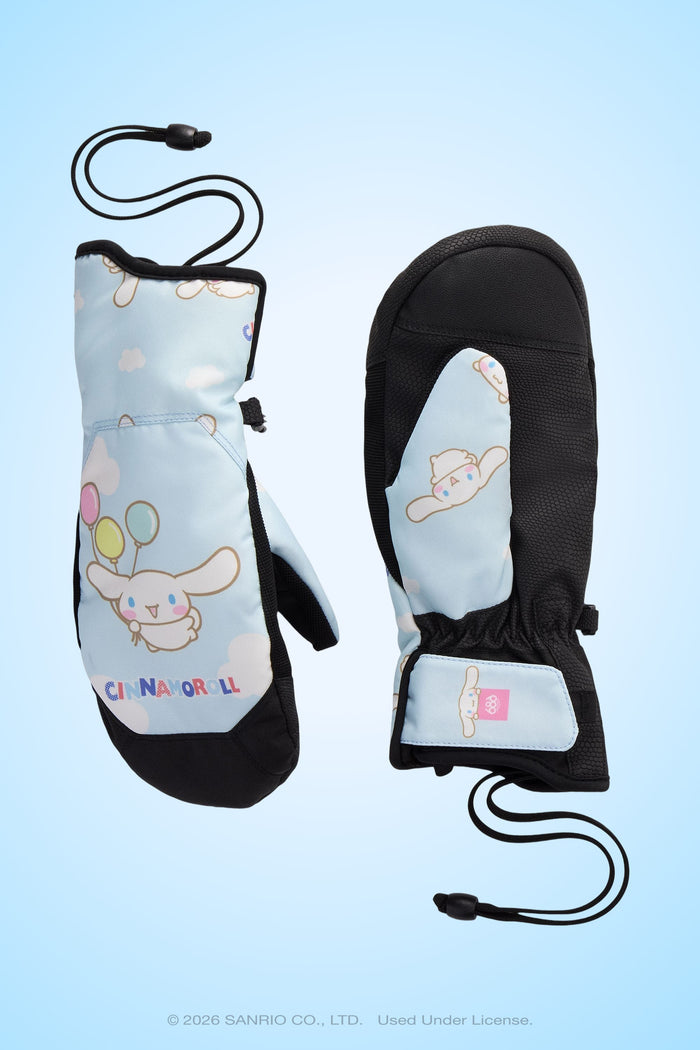 Light blue 686 Women’s Revel Mitts featuring Cinnamoroll character and balloon graphics. One mitt displays the front with a Velcro strap, while the other shows the palm side. Both have black palms, wrist cords, and are photographed on a light blue background.