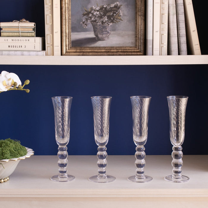Beatriz Ball Glass French Swirl Champagne Flute — Four matching flutes beneath a bookshelf