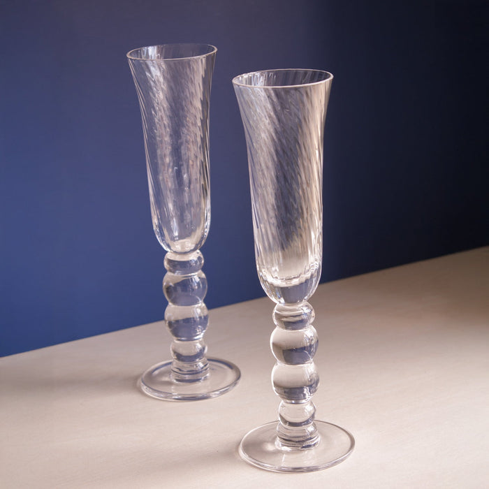 Beatriz Ball Glass French Swirl Champagne Flute — Two clear flutes beside books