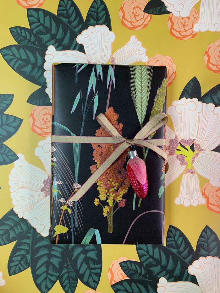 Gift wrapped in black paper with floral design on a floral-patterned background
