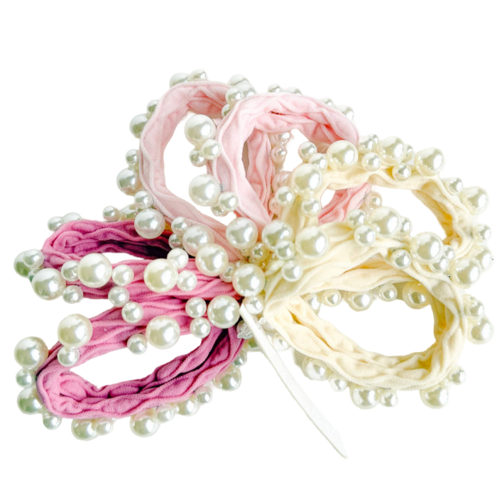 Two hair ties with pearl embellishments, one pink and one beige, on a white background.